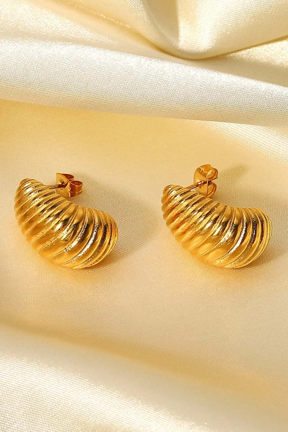 Gold Seashell Stud Earrings on satin background.