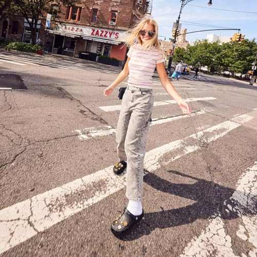 Crocs Unisex-Adult Classic Clogs in black worn outdoors by a person crossing a street.