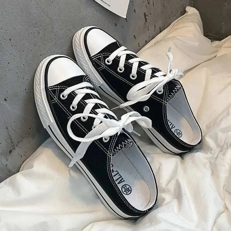 Round toe lace-up canvas sneakers with white laces and rubber soles on a casual setting.