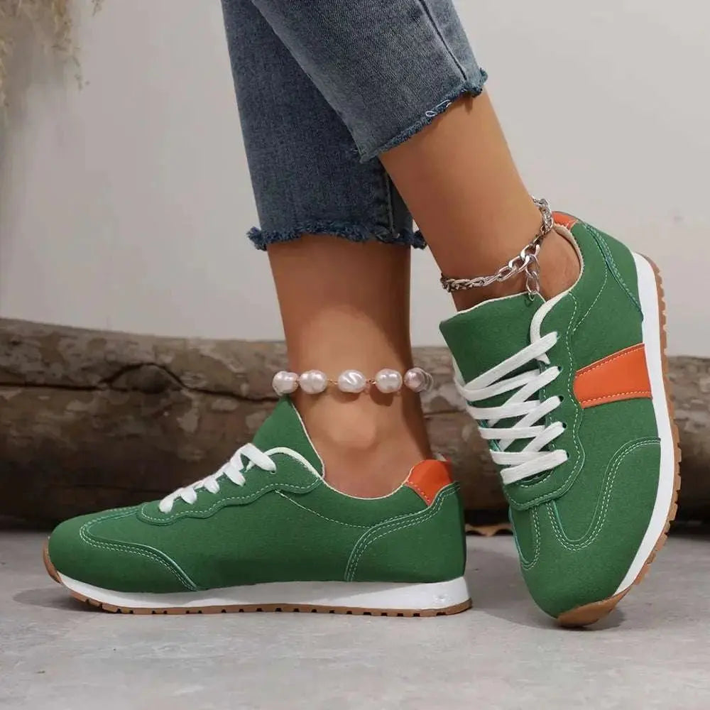 PU leather contrast round toe green flats sneakers with white and orange accents, worn with jeans.