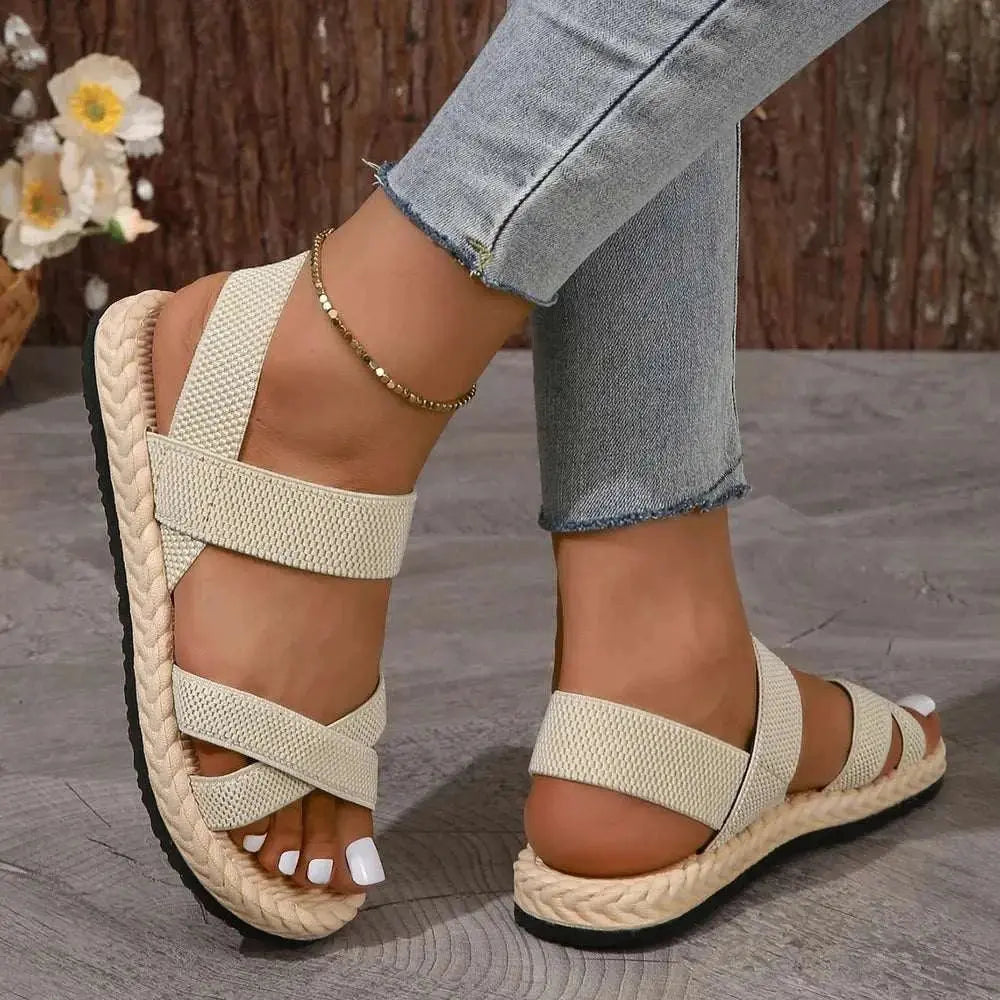 Crisscross open toe flat sandals in beige fabric with a rubber sole, casual style.