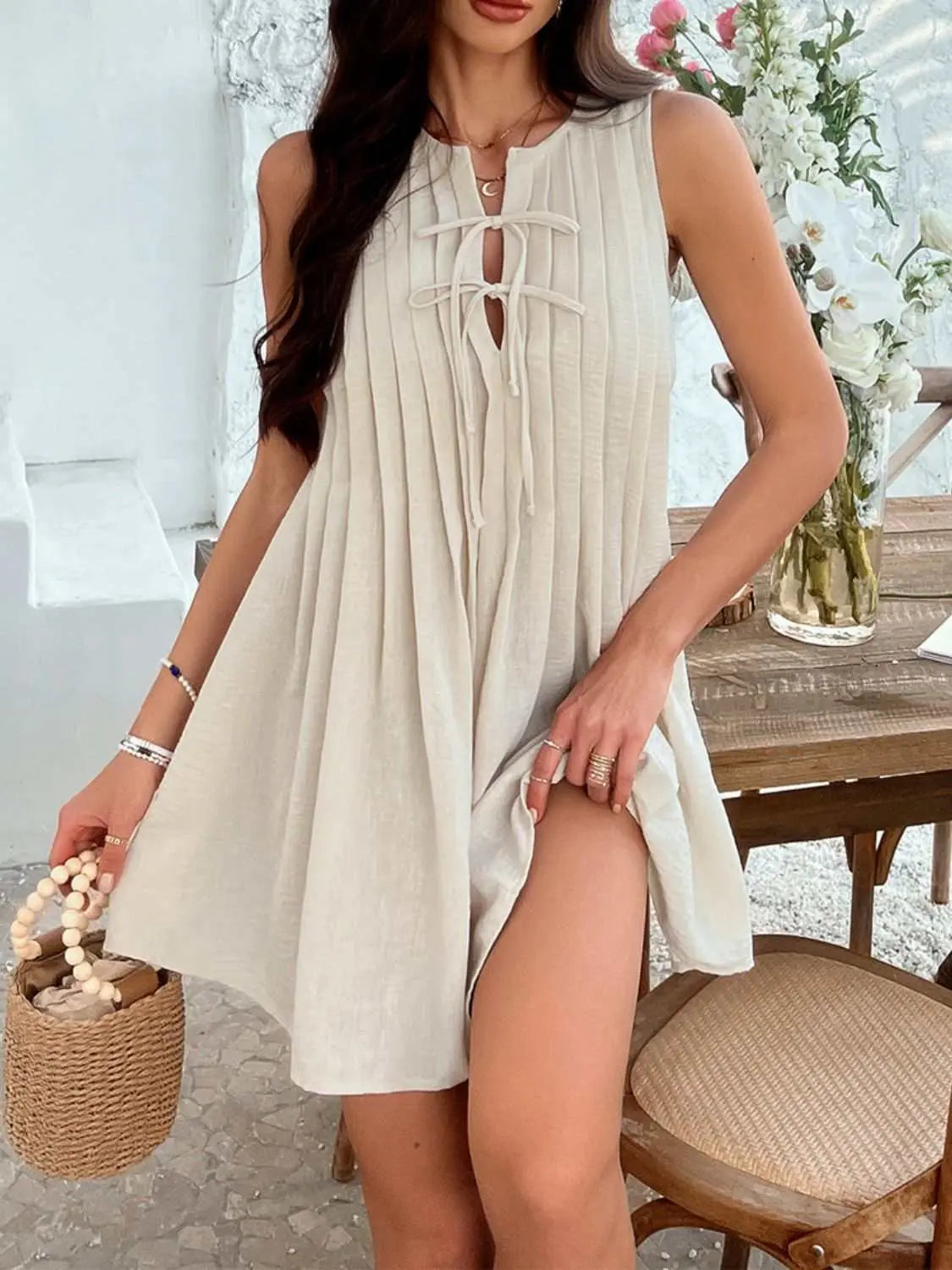 Devine Pleated Sleeveless Mini Dress with tie detail in beige, slightly stretchy polyester fabric.