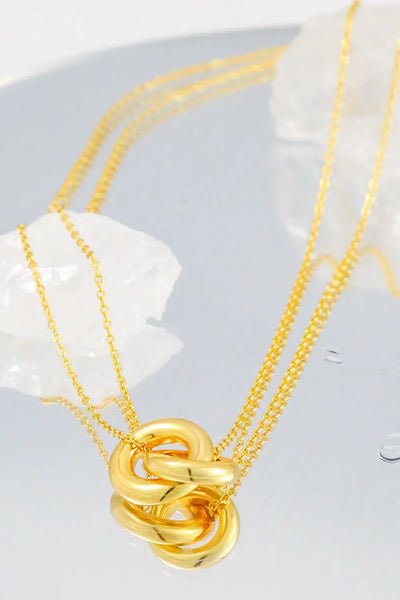 Linked ring pendant chain necklace in brass, elegant design, flat lay image.