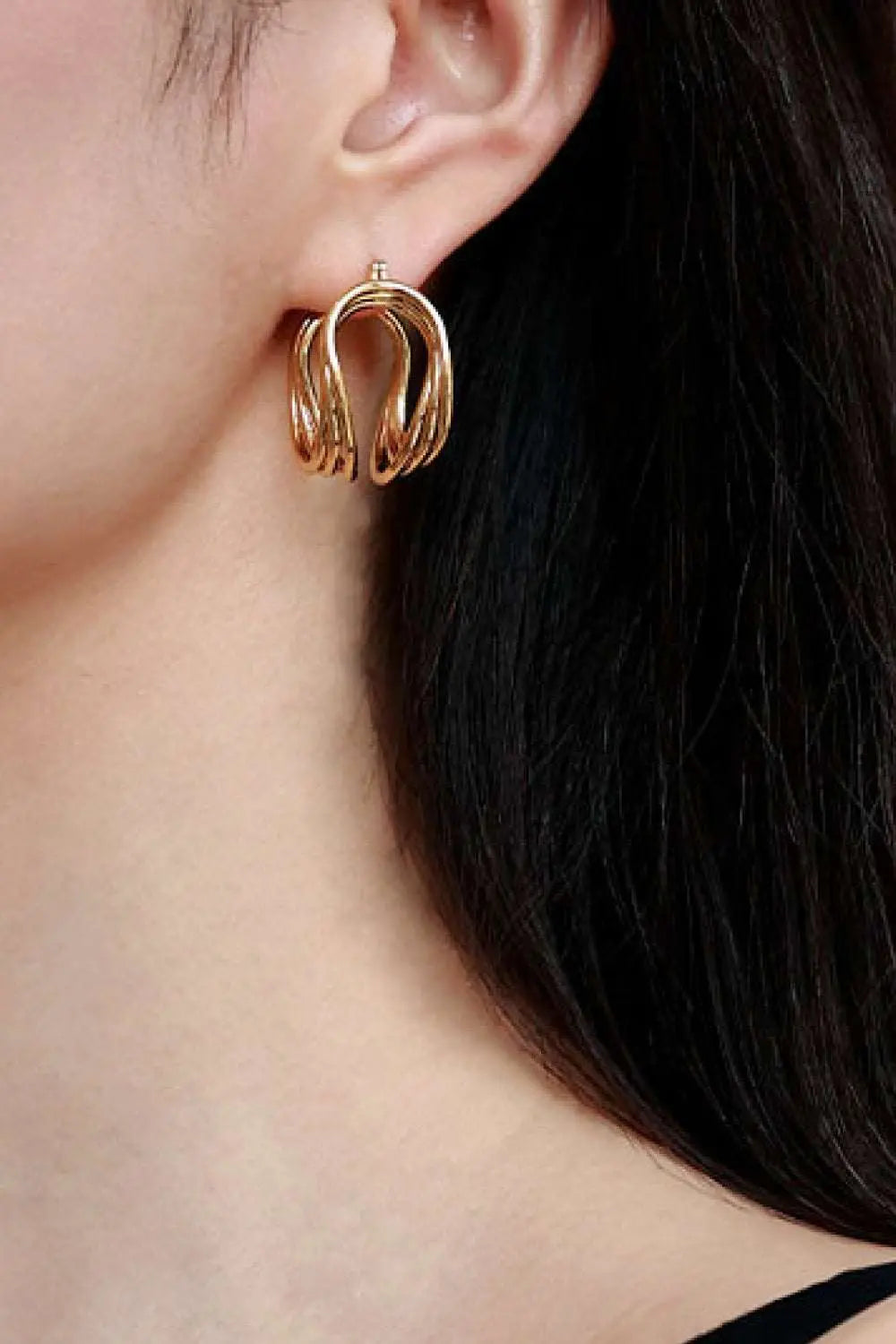 U-Shaped brass hoop earrings worn on an ear.