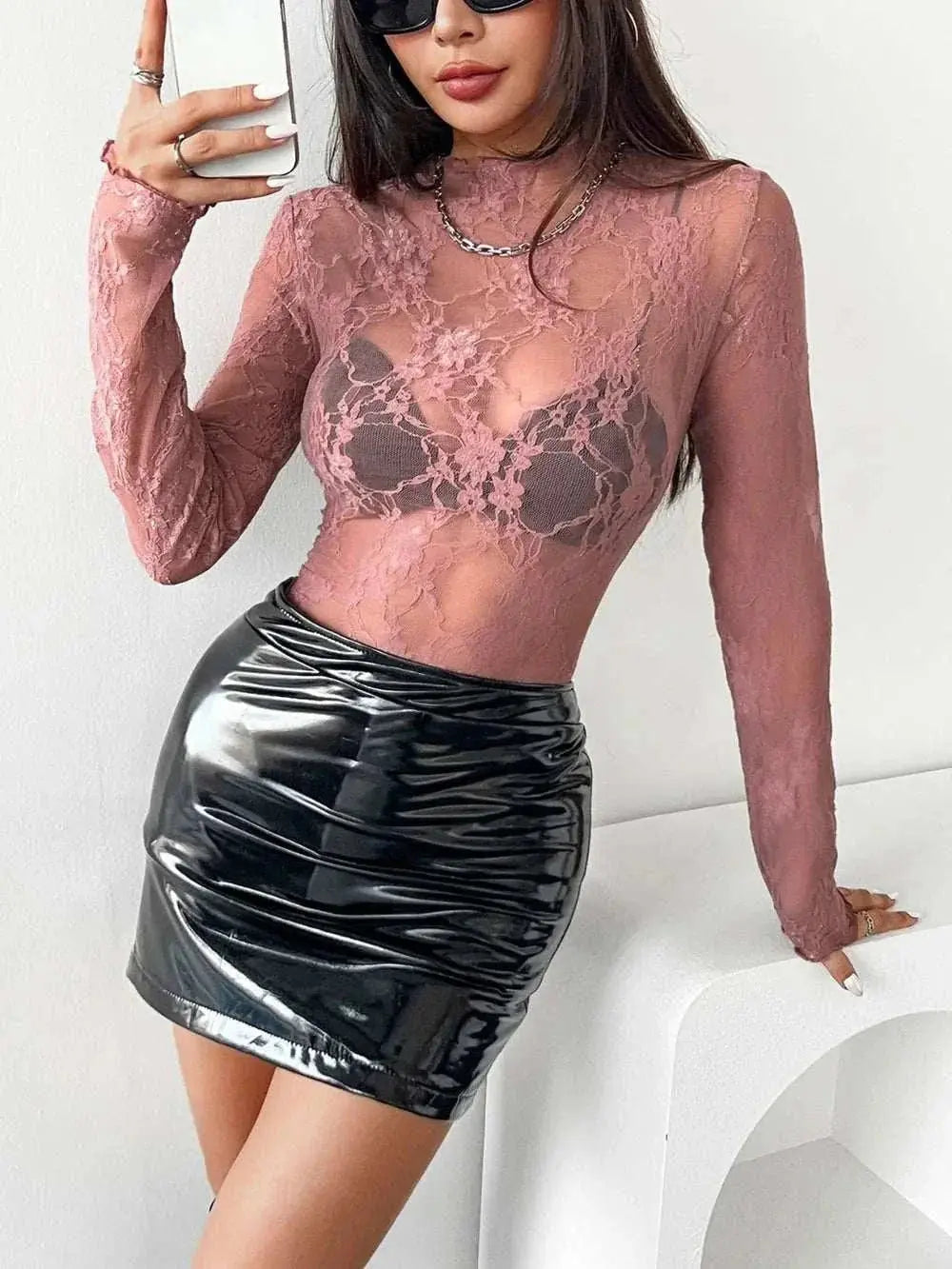 Mock neck long sleeve sheer lace top in pink paired with a black skirt.