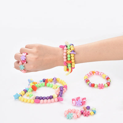 DIY handmade gift box for kids with colorful bead jewelry on a wrist and table.