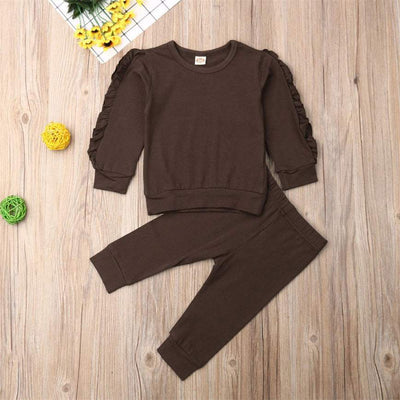 Newborn ruffle jumper 2-piece set with long sleeve top and pants in brown, displayed on a wooden surface with decorative items.
