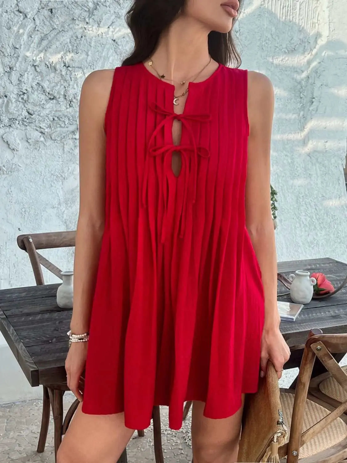 Devine Pleated Sleeveless Mini Dress in red with tie detail, slightly stretchy polyester fabric.
