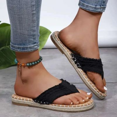 Toe post raw hem flat sandals in black canvas, rubber sole, worn with jeans.