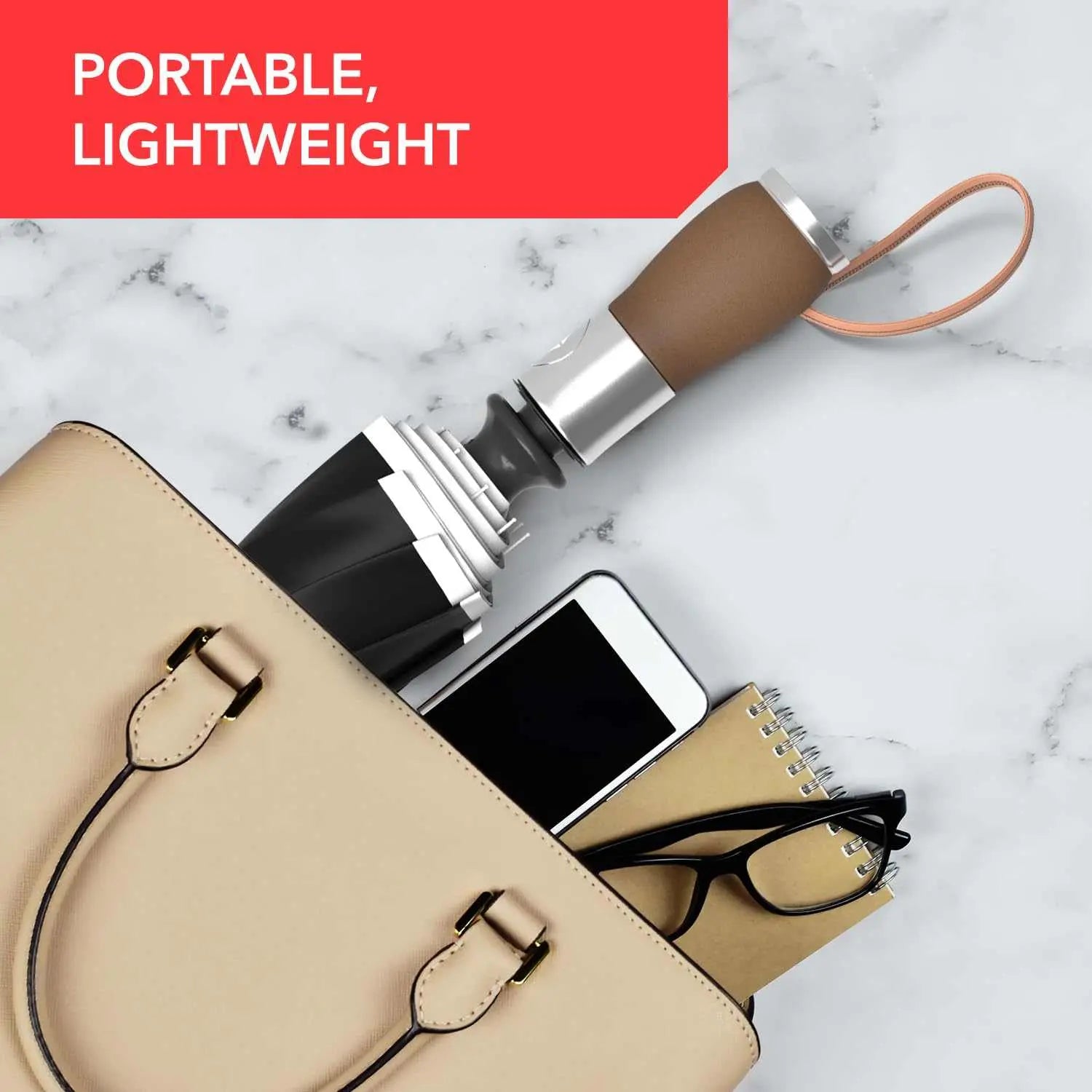 Portable, lightweight Repel umbrella in a purse with a phone, notebook, and glasses.