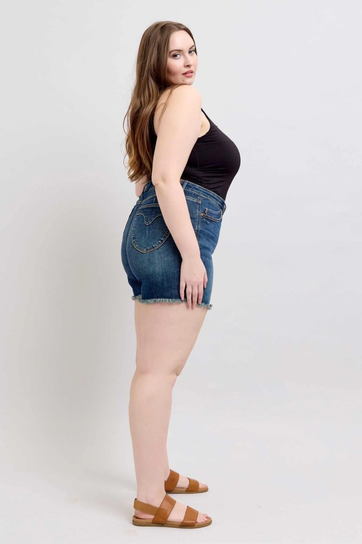 Judy Blue Tummy Control denim shorts with fray hem and shield back pockets featuring a slimming effect.