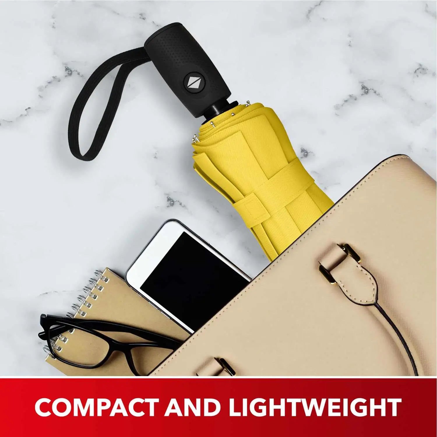 Compact and lightweight yellow Repel Umbrella Windproof in a beige bag alongside a notebook, glasses, and smartphone.