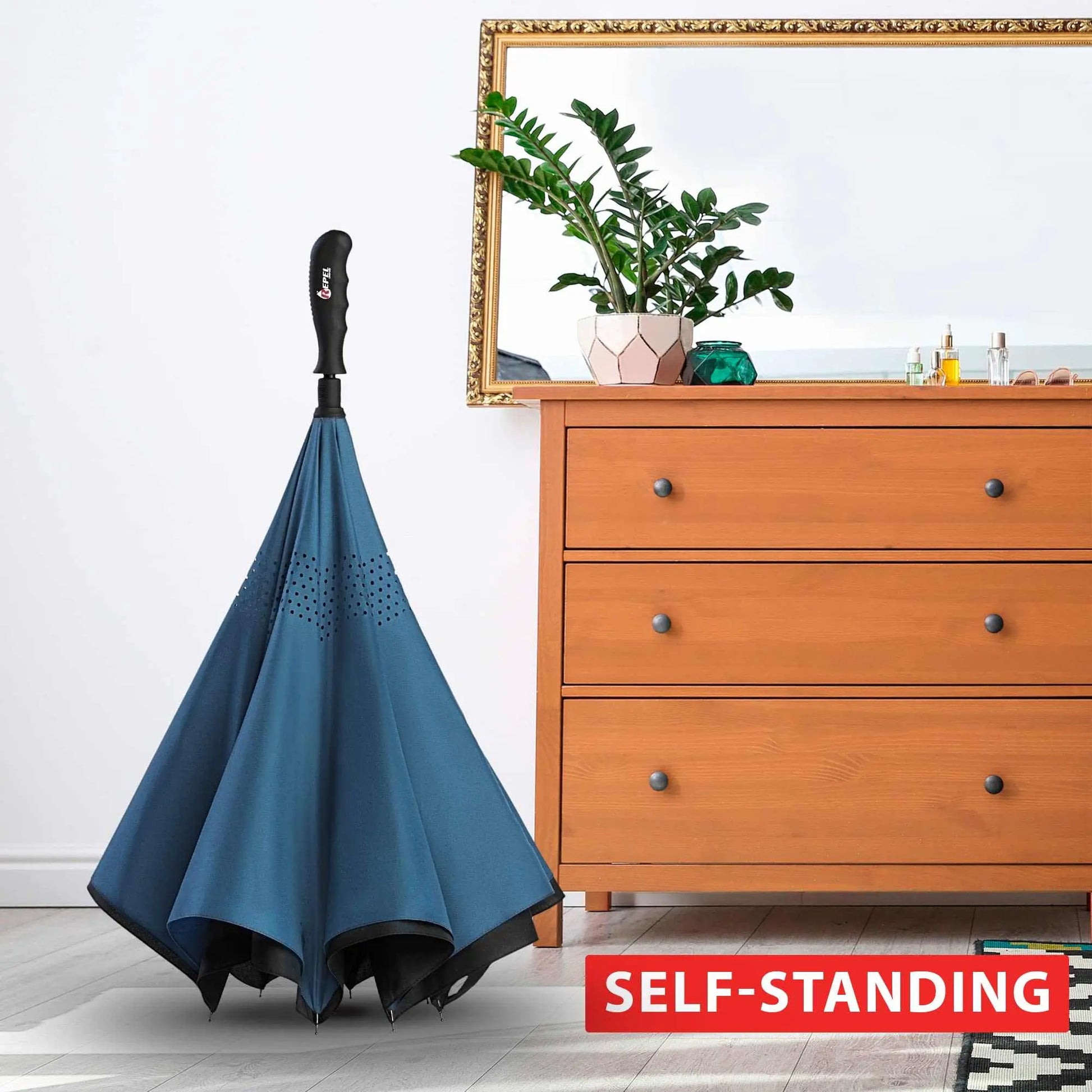 Repel Umbrella Windproof self-standing in a room setting next to a dresser.