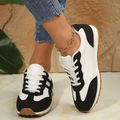 Contrast lace up round toe sneakers in black and white, worn with blue jeans.
