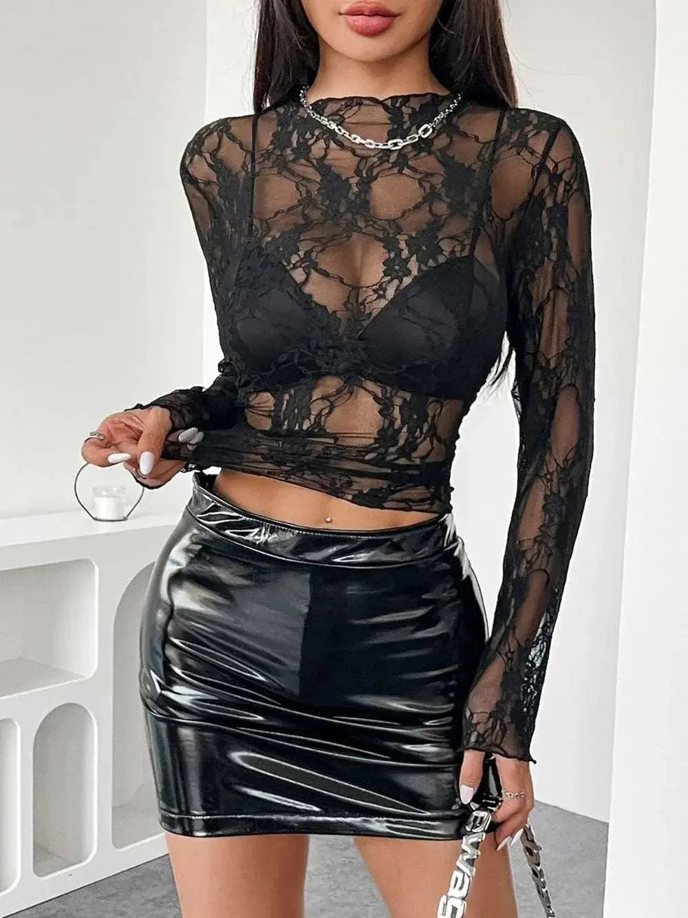 Mock neck long sleeve sheer lace top in black paired with a shiny black skirt.