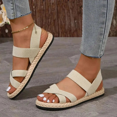 Crisscross open toe flat sandals in rubber and cloth material.