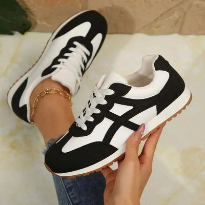 Contrast Lace Up Round Toe Sneakers in black and white with PU leather and rubber material, worn by a person.