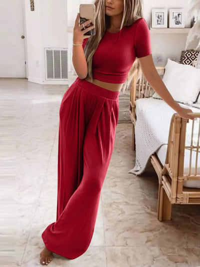 Plus size round neck short sleeve top and pants set in red, displayed on a model in a minimalist room.