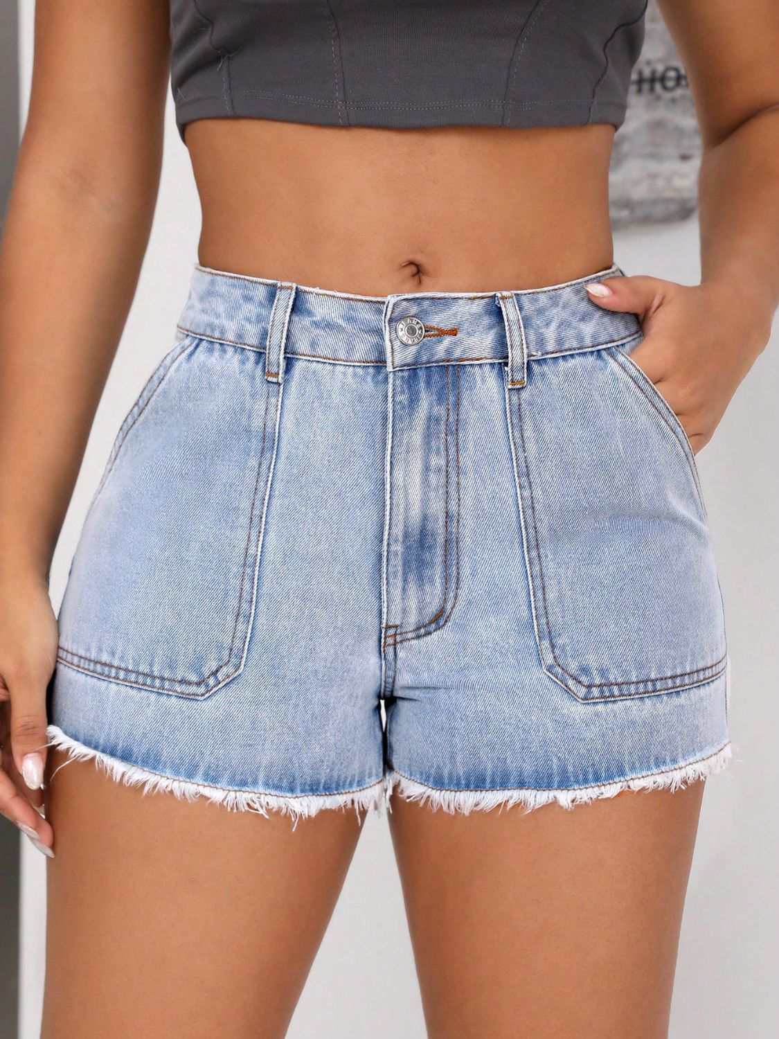 Raw hem pocketed denim shorts with button closure and fringe detail.