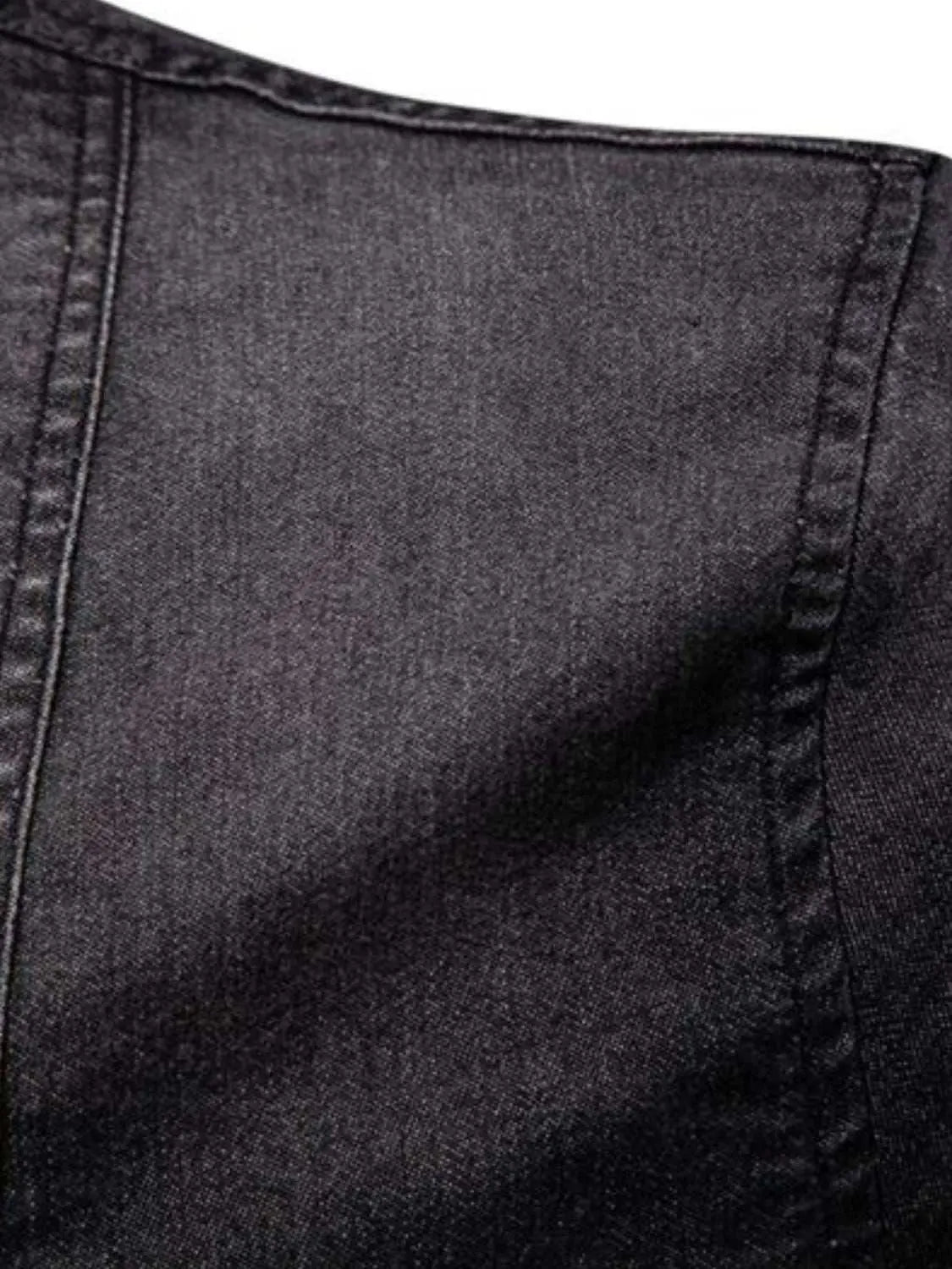 Close-up of a men's black denim fabric, highlighting stitching detail.