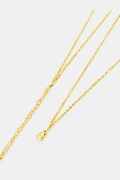 Linked ring pendant chain necklace in brass on flat lay background.