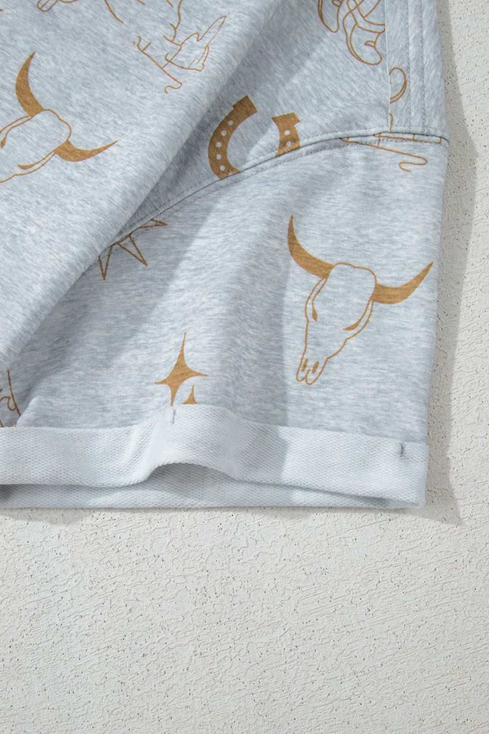Printed T-shirt with western-themed graphics including skulls and horseshoes on light gray fabric.