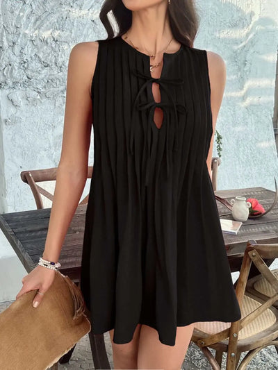 Devine Pleated Sleeveless Mini Dress in black with tie details, slightly stretchy polyester fabric.