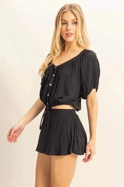 Drawstring hem short sleeve top and skort set in black, featuring button details and a ruched design.
