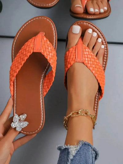 Braided toe post flats sandals in orange with rubber and PU material.